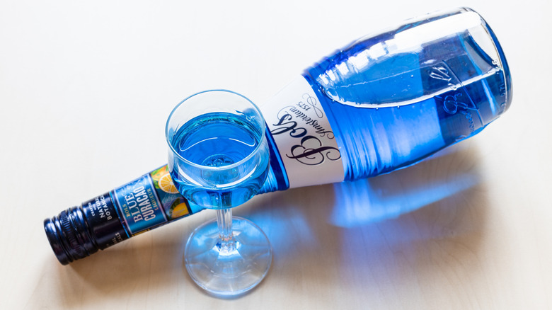 Bottle and small glass of blue curaçao liqueur