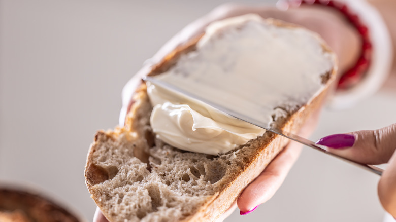 Woman's hand spreading butter on toast.