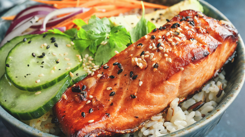 Spicy salmon rice bowl with cucumbers, red onions, carrots, and cilantro