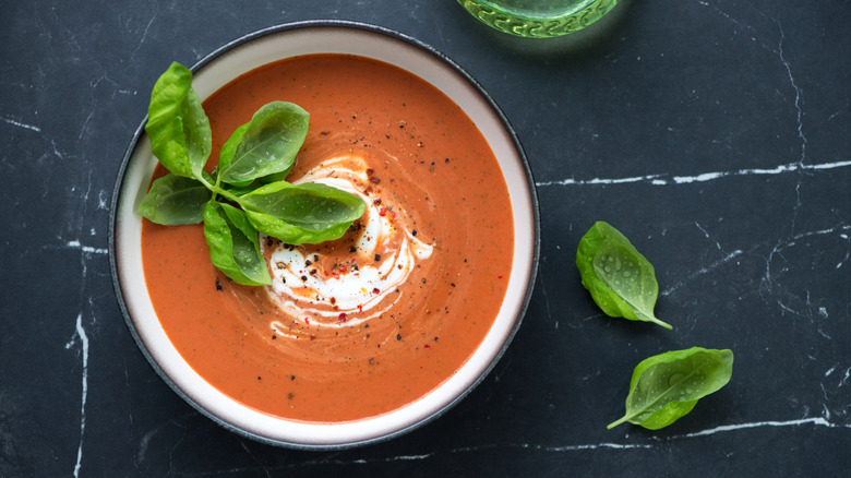 A bowl of tomato soup with cream and fresh basil