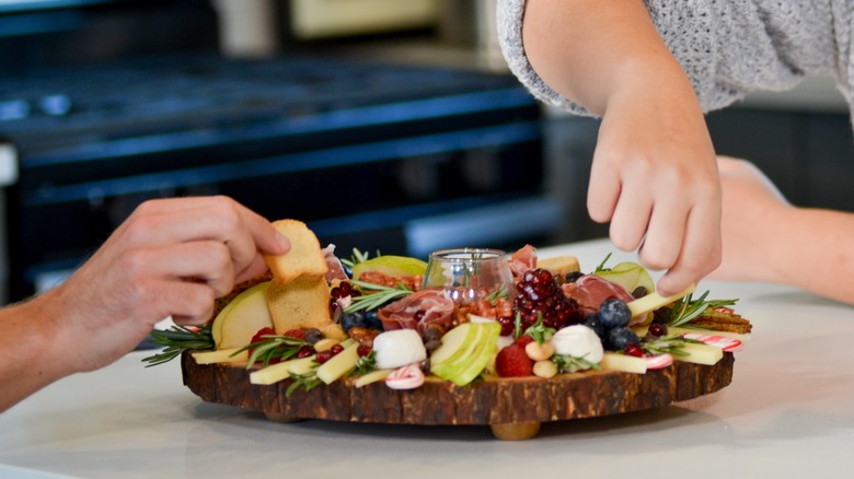 charcuterie board with meat and cheese being enjoyed by two people