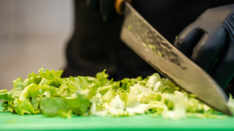 Lettuce being chopped by a large knife