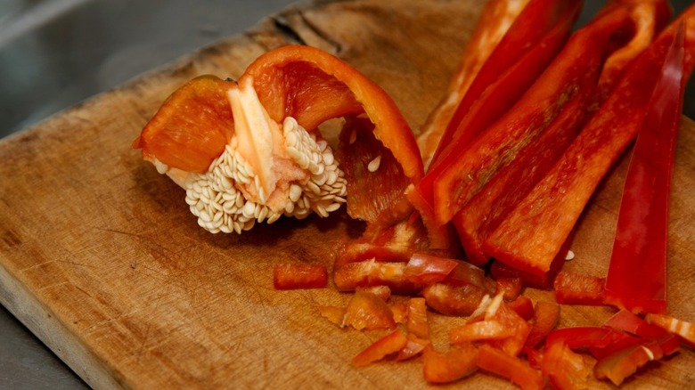 Sliced bell pepper stem and seeds laying on cutting board