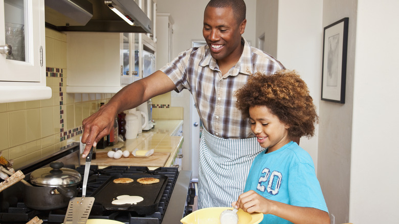 A dad making pancakes with his daughter using a griddle