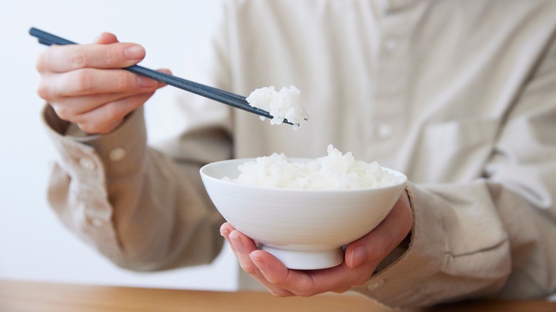 Person eating white rice in bowl