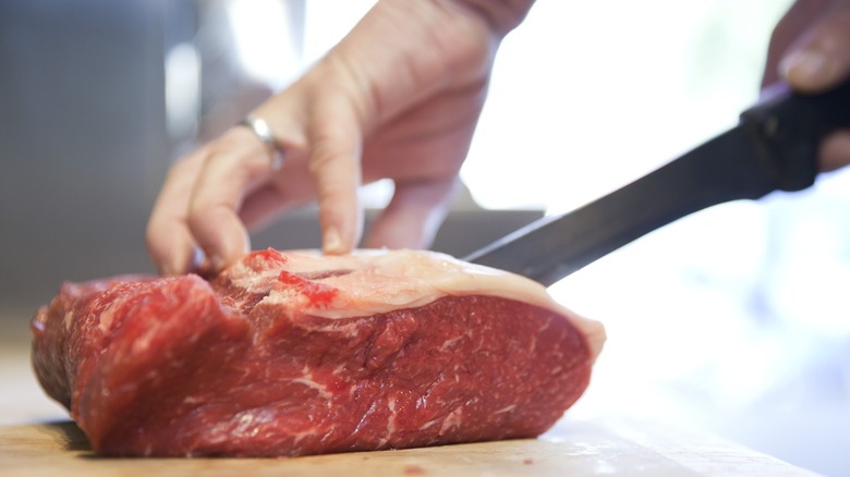 A butcher cutting steaks from a piece of meat.