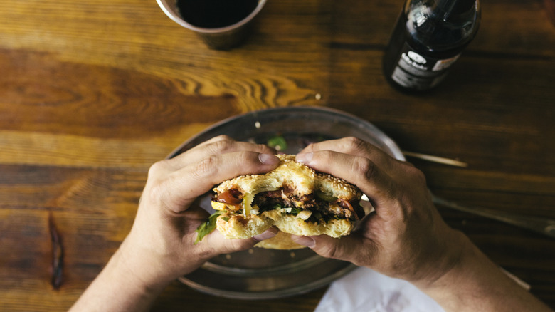 Person holds half-eaten burger