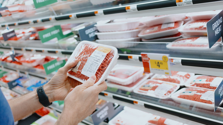 Person holds ground beef package in grocery store