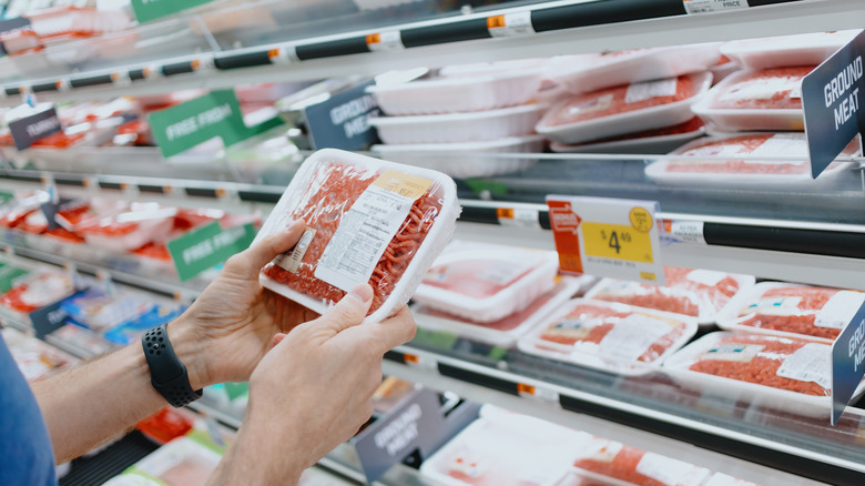 person holding a package of ground chuck at the store