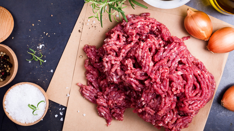 ground beef sitting on parchment paper with ingredients around it