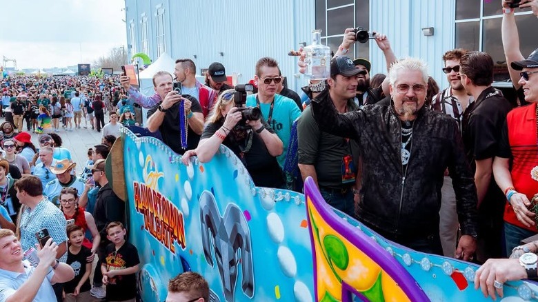 Guy Firei holds bottle of tequila on mardi gras float, Flavortown Tailgate