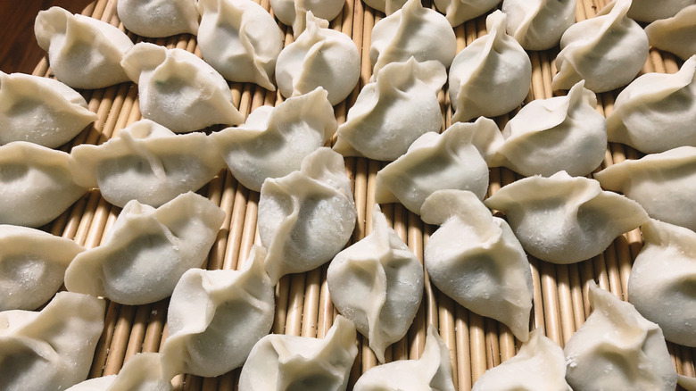 Raw Chinese dumplings on a bamboo mat