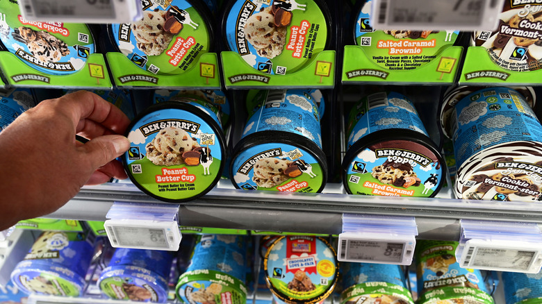 Person reaching into a store cooler for a pint of ice cream