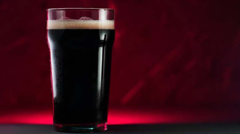 Pint glass of porter beer against a reddish background