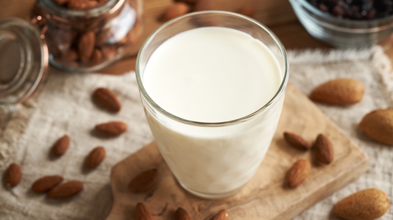 glass of almond milk surrounded by almonds