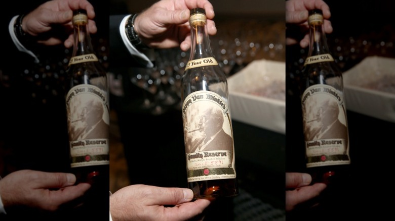 hand holding Pappy Van Winkle whiskey bottle