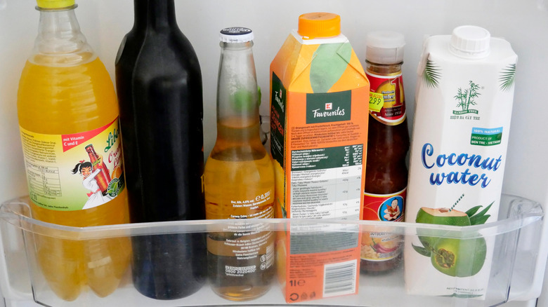 six bottles of different liquids in a fridge door shelf