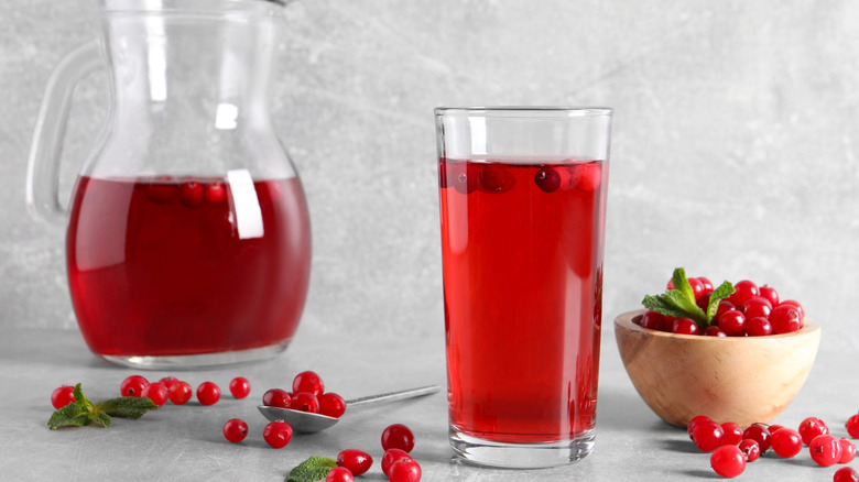 Pitcher and glass of cranberry juice with fresh cranberries