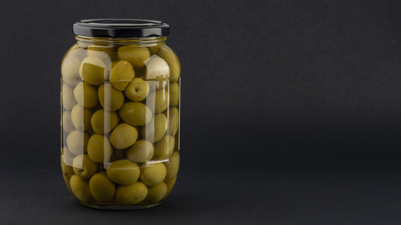 a jar of olives against a dark background