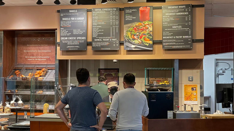 Two men ordering food at the counter of a Panera Bread.