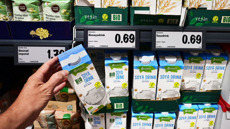 hand holding a carton of soy milk in supermarket