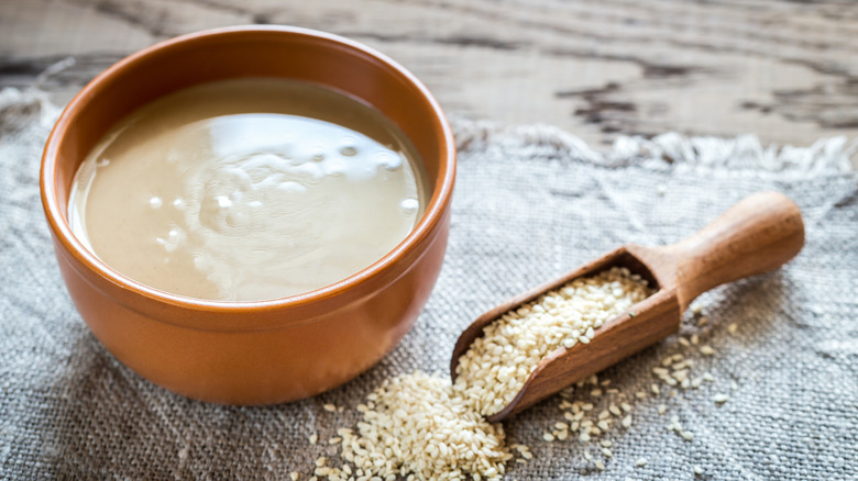 Tahini in a bowl with a scoop of sesame seeds