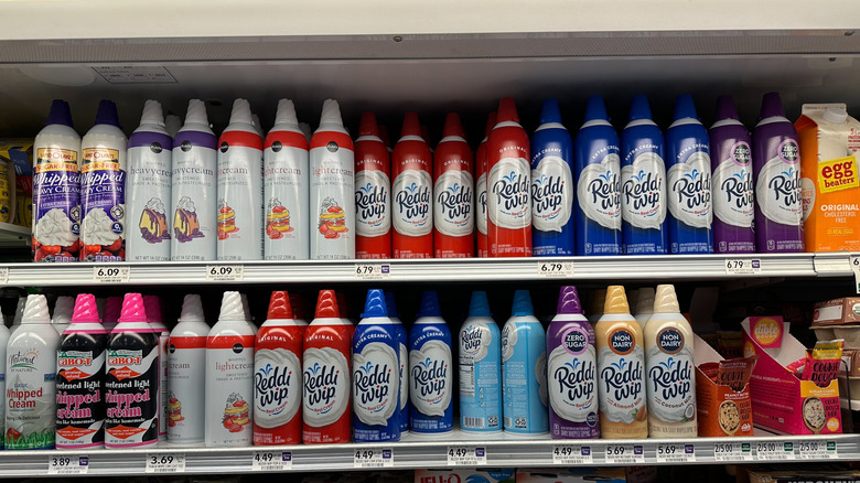 Cans of Reddi-wip cream on a grocery store shelf