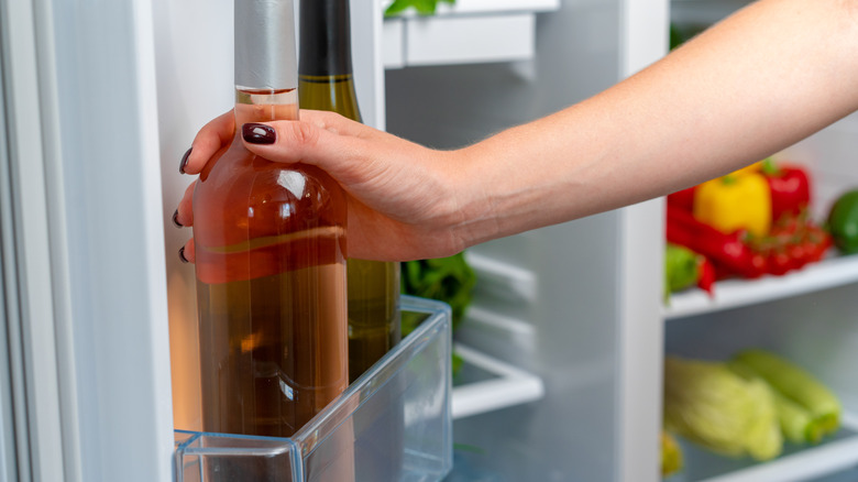 Hand placing wine in fridge