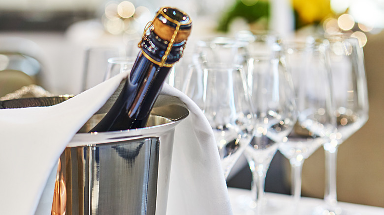 chilled champagne in an ice bucket with empty glasses behind