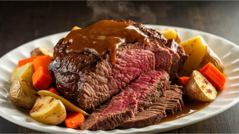 Up close picture of pot roast with carrots, onions, potatoes, herbs, spices, and gravy