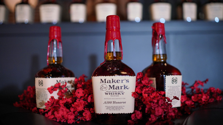 Three bottles of Maker's Mark are nestled among flowers