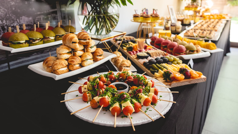 Assorted appetizers like caprese skewers and sandwiches arranged on a table