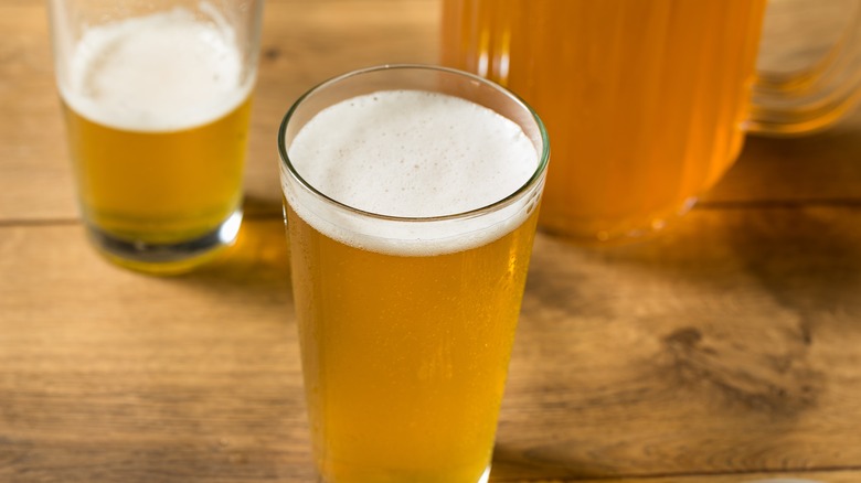 A pint glass of beer with foam on top