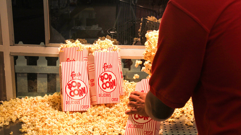 A person scooping popcorn into bags