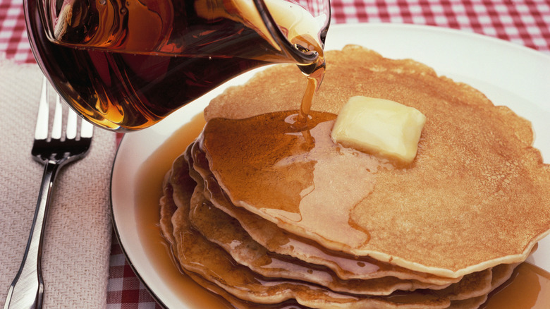 Bottle of syrup being poured on pancakes