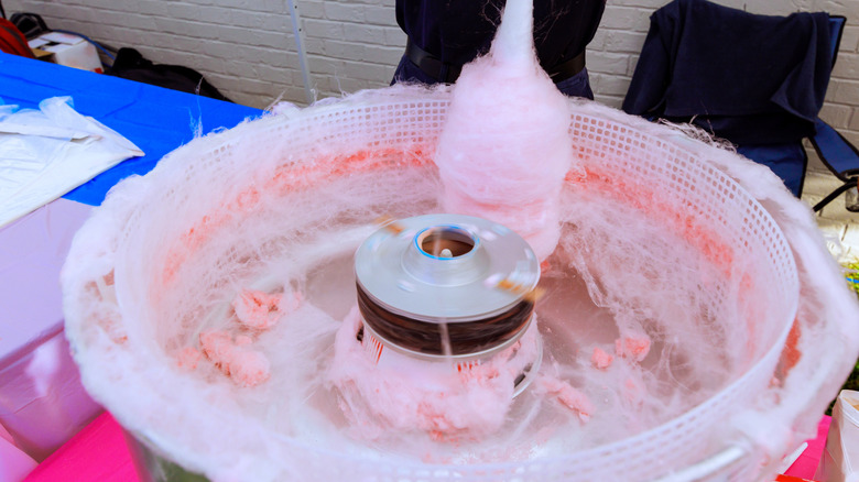 A vendor making cotton candy in a cotton candy machine