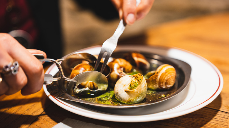 A close up of someone eating escargot.