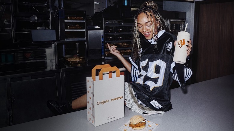 Woman with Don Julio Popeyes chicken sandwich and drink