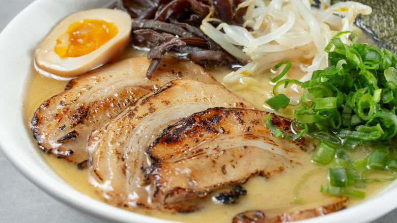 Close-up view of a bowl of miso ramen with pork, green onions, and egg