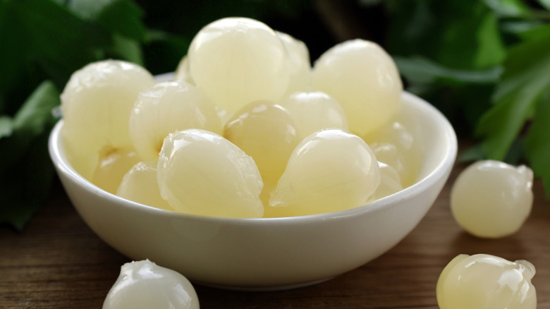 Small bowl of peeled pearl onions on a wooden table