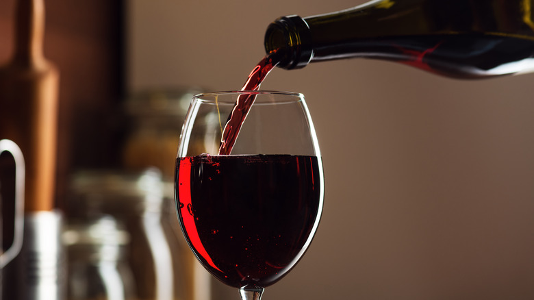 red wine being poured out of a bottle into a glass