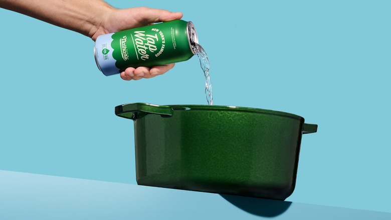 A hand pouring a can of Nathan's Famous New York Tap Water into a green pot.