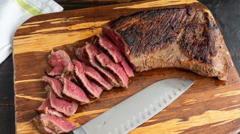 A steak being marinaded with a brush.