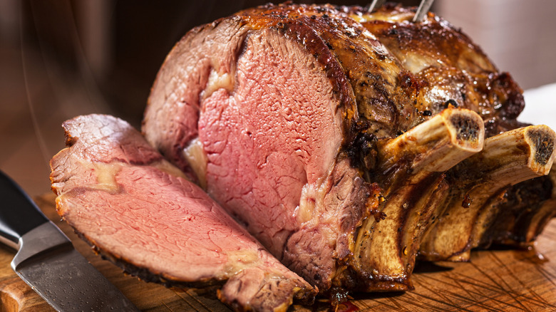 Juicy prime rib cooked medium rare and sliced on a wooden cutting board