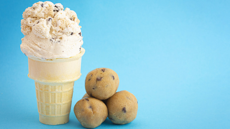 cookie dough ice cream in a cone with balls of cookie dough on the side