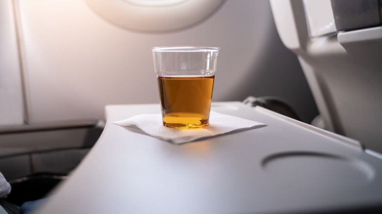 plastic cup of amber liquid on an airplane tray