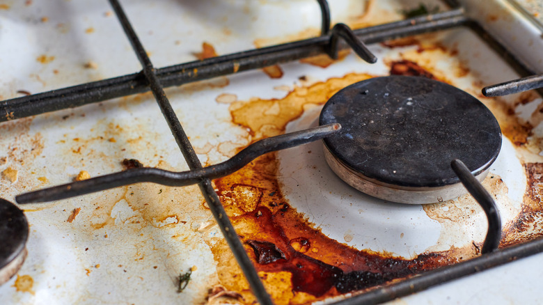 A dirty gas stovetop covered in oil, grease, and food stains