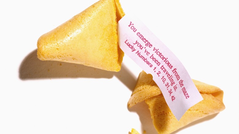 Broken Fortune cookie with note containing fortune and lucky numbers.