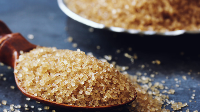 Brown sugar crystals spill out of a spoon