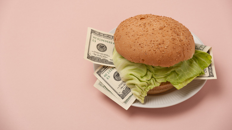 Hamburger on a white plate with money in the middle